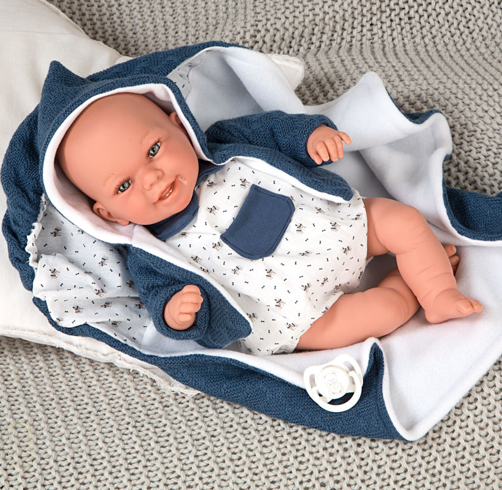 Muñeca con peso Elegance Babyto de Arias vestida con ranita azul con estrellas blancas sobre cojín beige texturizado.