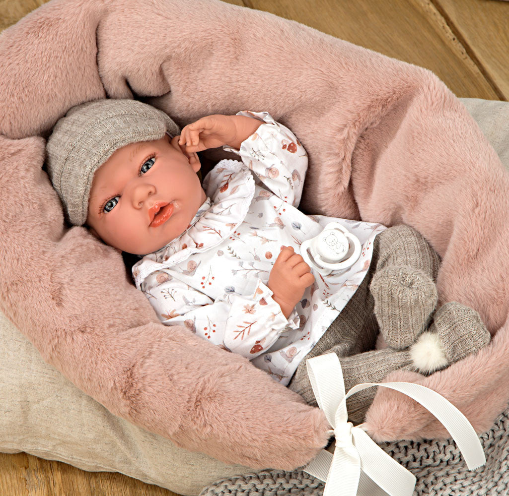 Muñeco con peso Elegance Andie de Arias con conjunto blanco y gorrito gris tumbado en su cojín de estrellas.