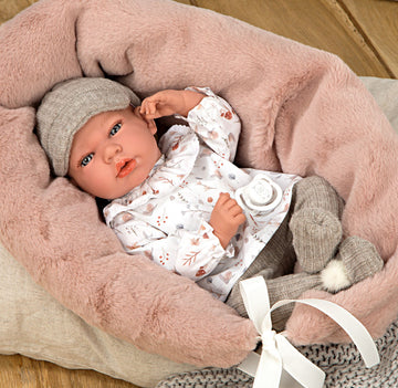 Muñeco con peso Elegance Andie de Arias con conjunto blanco y gorrito gris tumbado en su cojín de estrellas.