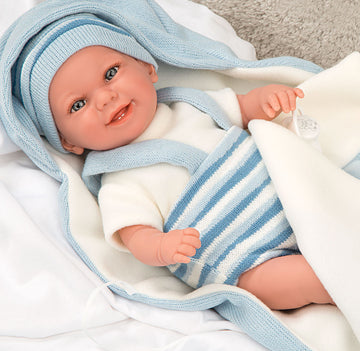 Muñeca con peso Elegance Babyto de Arias vestida con pelele de rayas blancas y azules sobre su cojín a juego.