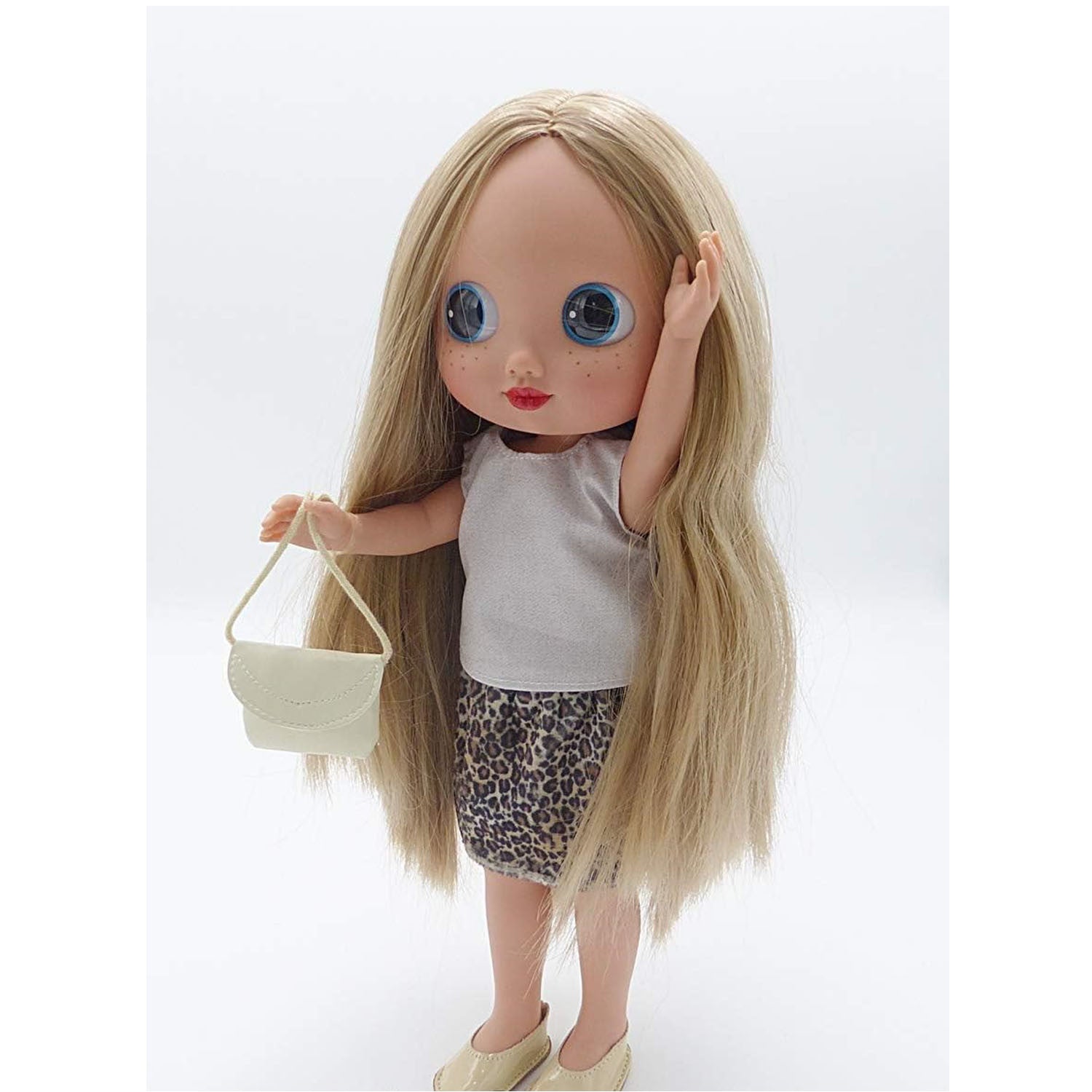 Muñeca Dunya Arias 38 cm de frente con grandes ojos azules, pelo largo y bolso beige