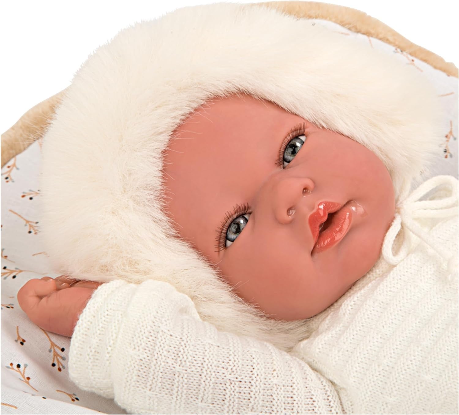 Detalle de perfil de la cabeza de la muñeca Reborn Alejandra de Arias luciendo su gorrito de punto beige con pompón.