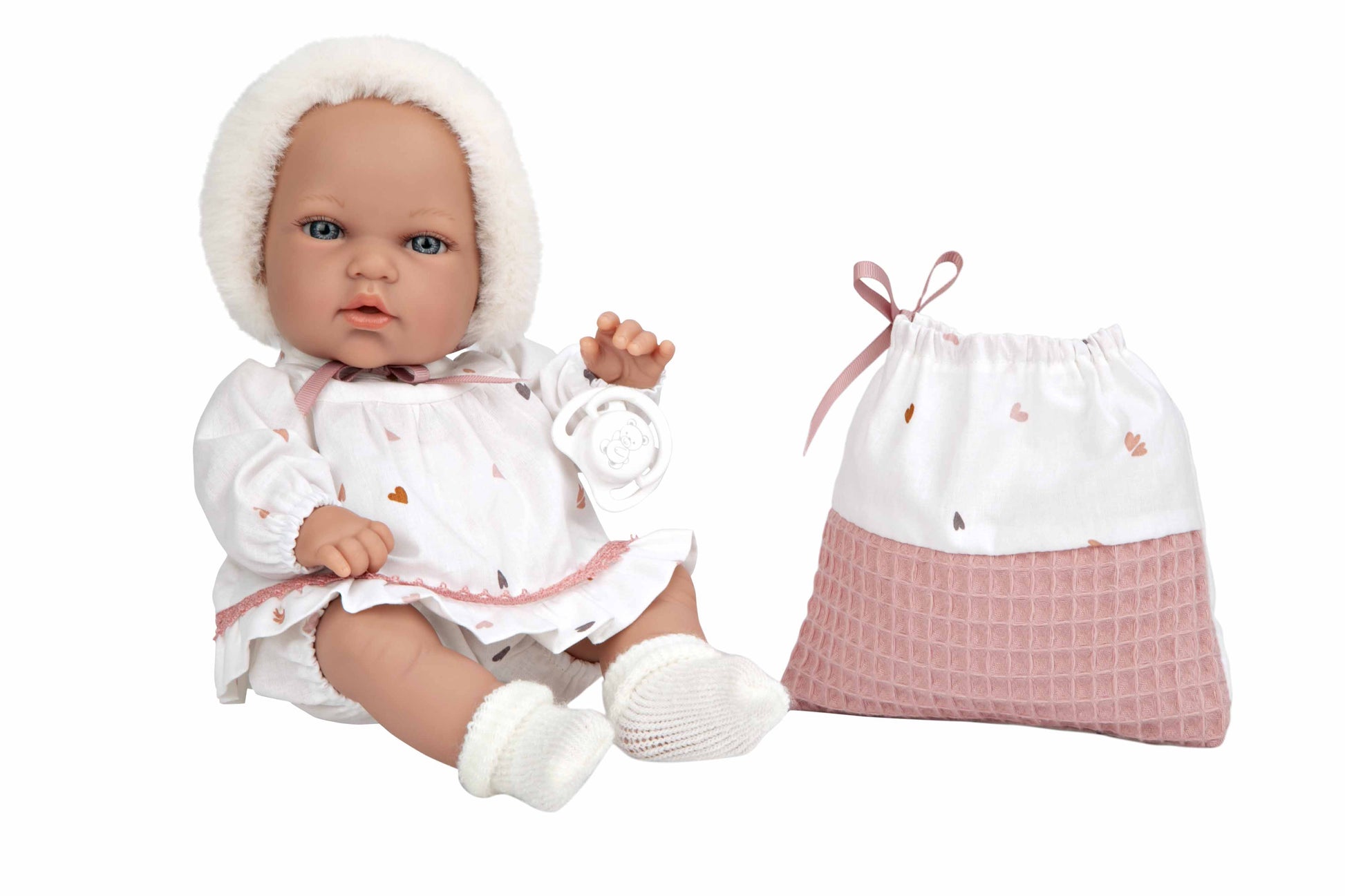 Muñeca pequeña Natal de Muñecas Arias de cuerpo blandito recostada sobre una superficie blanca neutra.