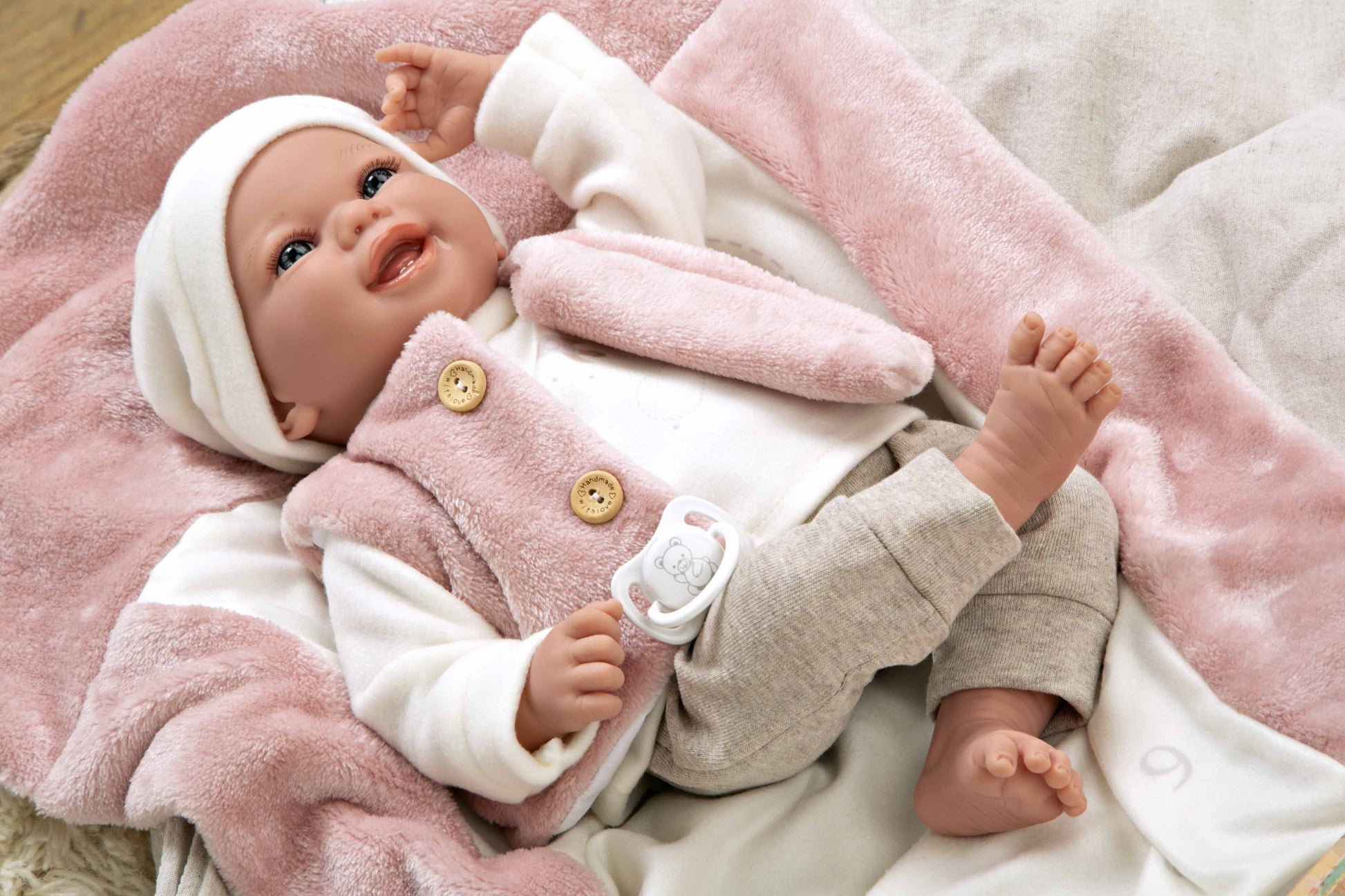 Muñeca de vinilo Colin de Muñecas Arias estirada boca arriba en su colchón, ideal para aprender jugando de verdad.