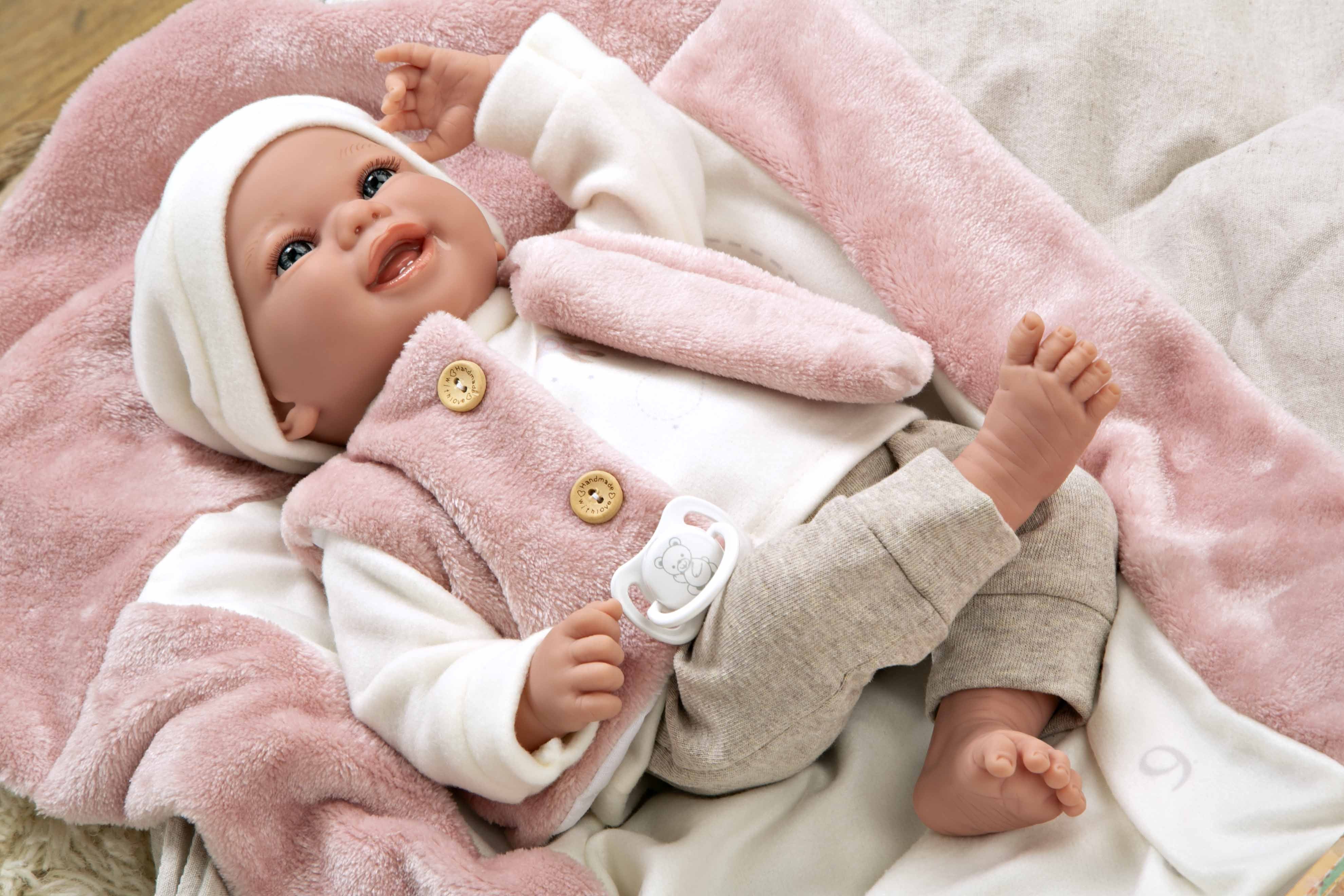 Muñeca de vinilo Colin de Muñecas Arias estirada boca arriba en su colchón, ideal para aprender jugando de verdad.