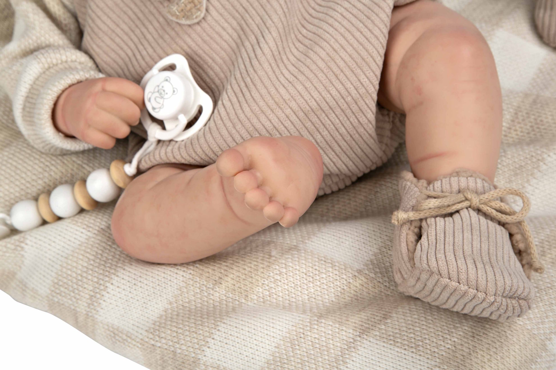 Primer plano de los pies realistas de la muñeca Reborn Rubén de Arias mostrando las arrugas de la piel de vinilo.