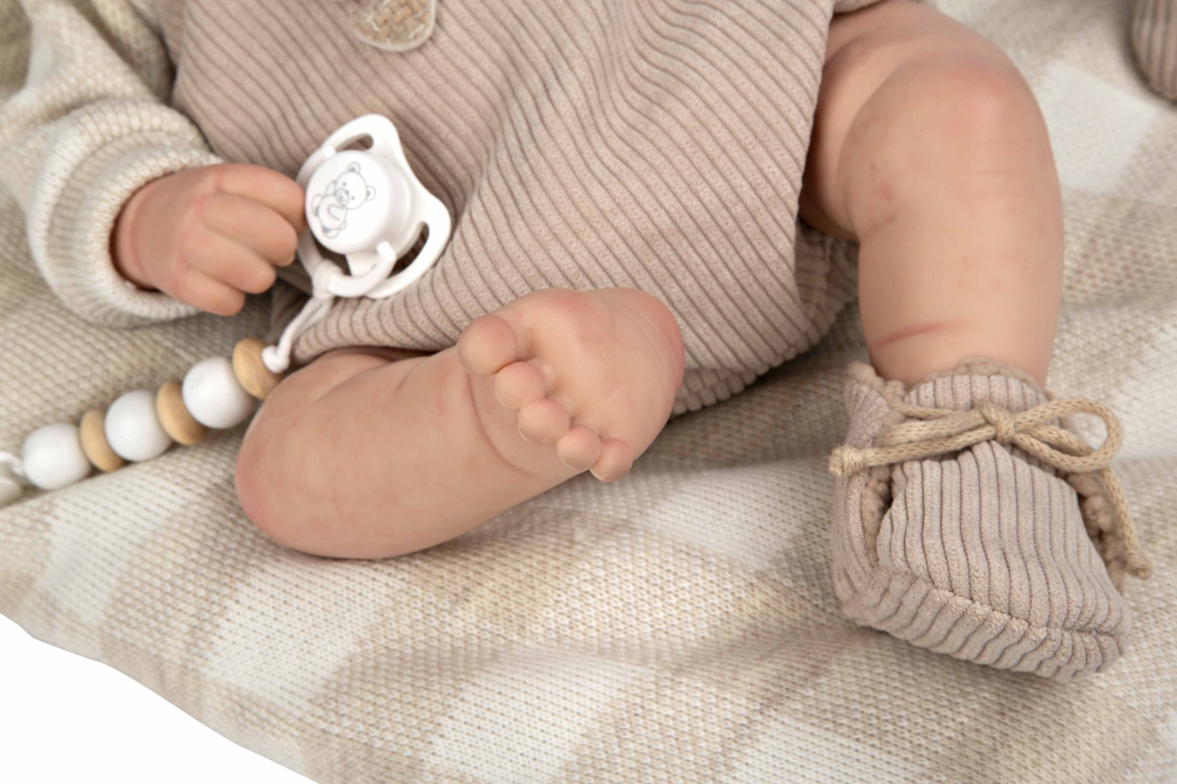 Primer plano de los pies realistas de la muñeca Reborn Rubén de Arias mostrando las arrugas de la piel de vinilo.
