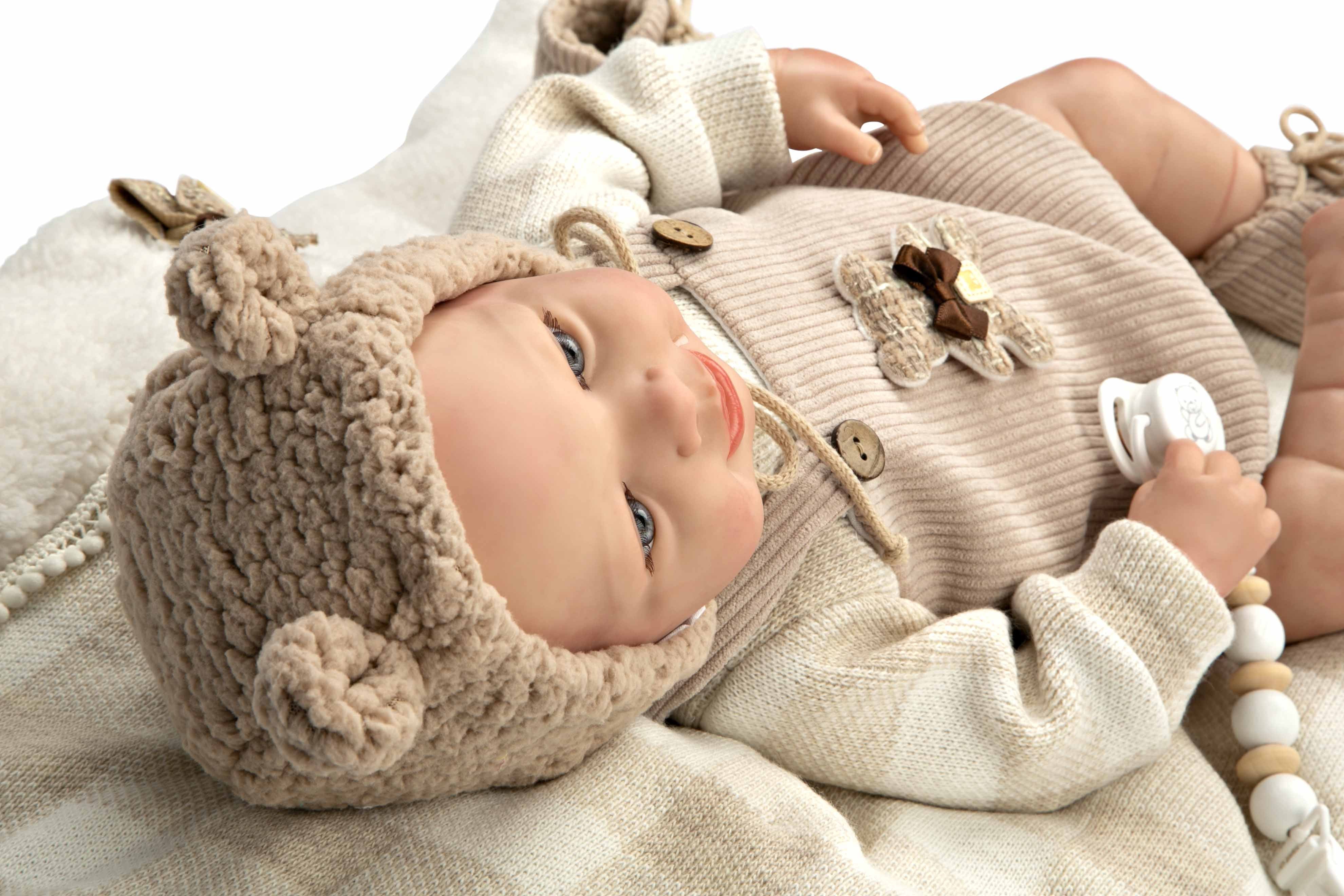 Detalle de perfil del rostro hiperrealista del muñeco Reborn Rubén de Arias mostrando el acabado blando y su gorrito con orejas.