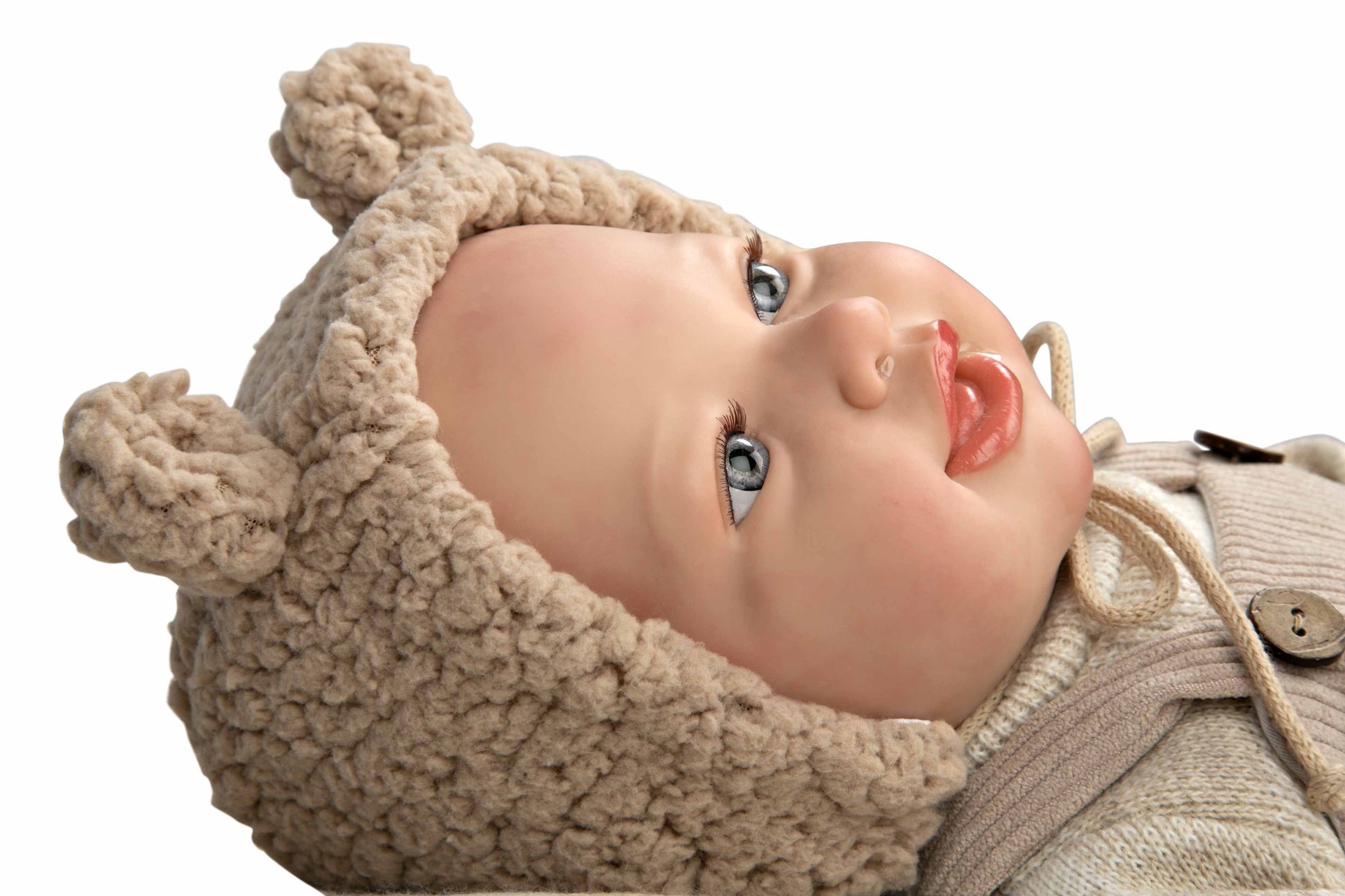 Facciones de recién nacido en la carita de la muñeca de vinilo de Arias con gorro de lana texturizado color beige.
