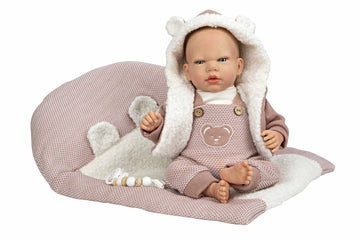 Muñeca Reborn Gadea de Arias de cuarenta centímetros con conjunto rosa de punto sentada en su cojín nido blanco.