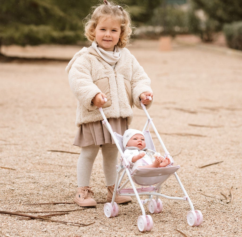 Niña paseando la silla de paseo Emma de Arias con muñeca bebé en exterior, juego simbólico