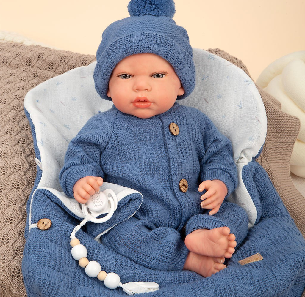 Bebé Reborn Alberto Arias 40 cm sentado con gorro y conjunto de lana azul, vista frontal