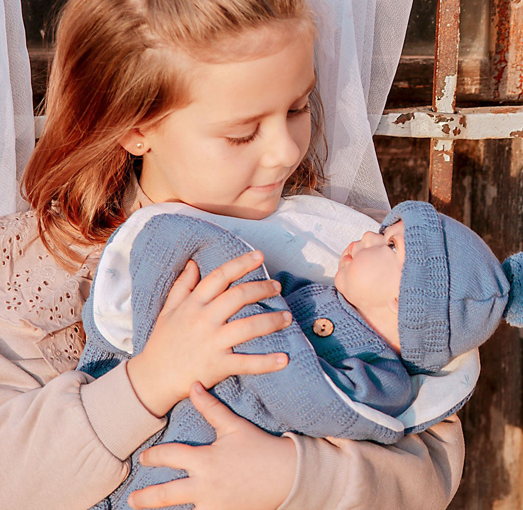 Niña sosteniendo el Bebé Reborn Alberto de Arias con conjunto de lana azul