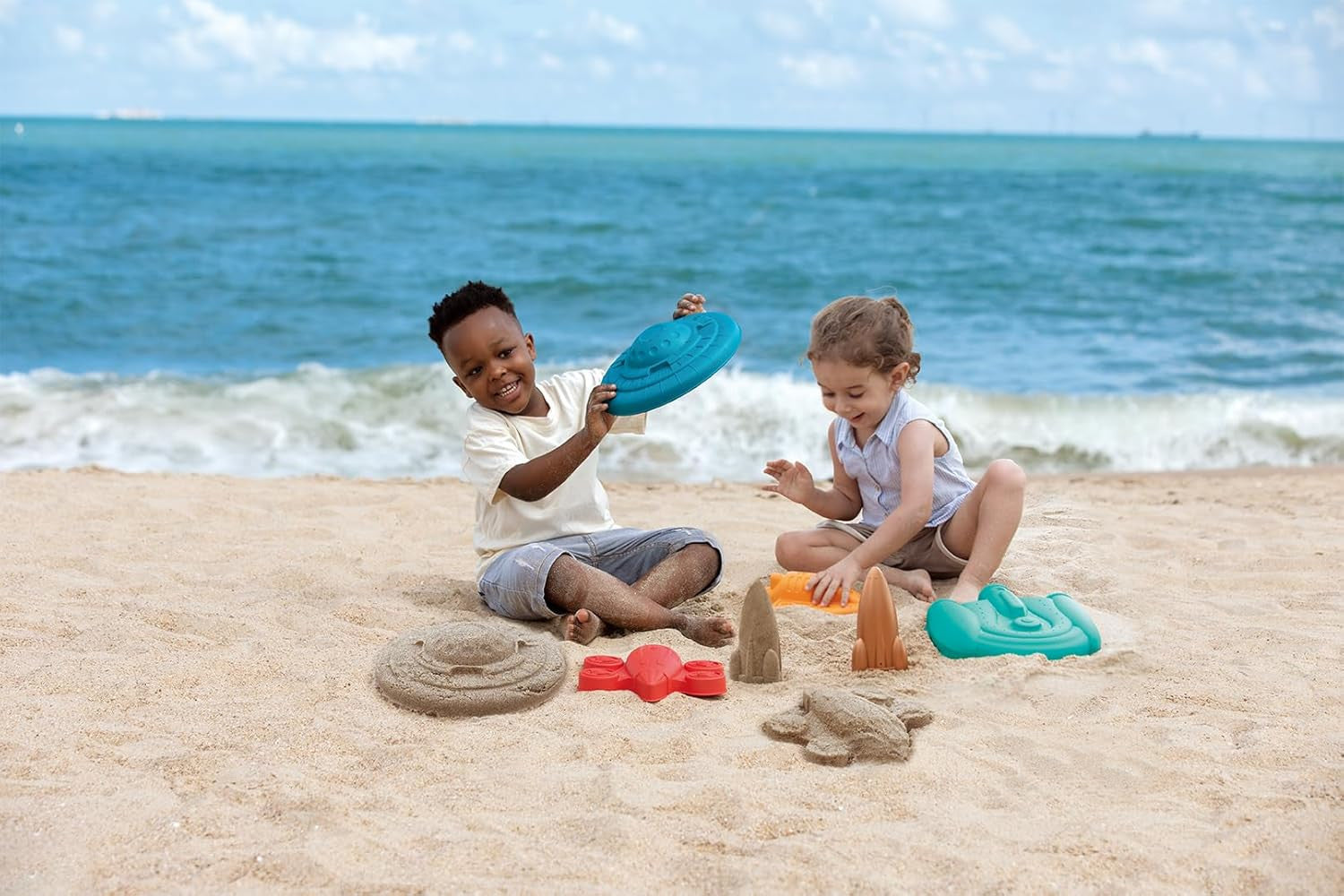Niños jugando en la playa con el set de moldes espaciales Hape – juego de arena y agua desde 18 meses al aire libre
