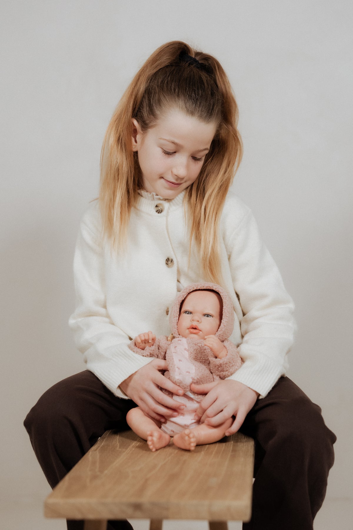 Niña sentada sosteniendo la Muñeca Reborn Luna Rosa de Muñecas Arias con su manta nido