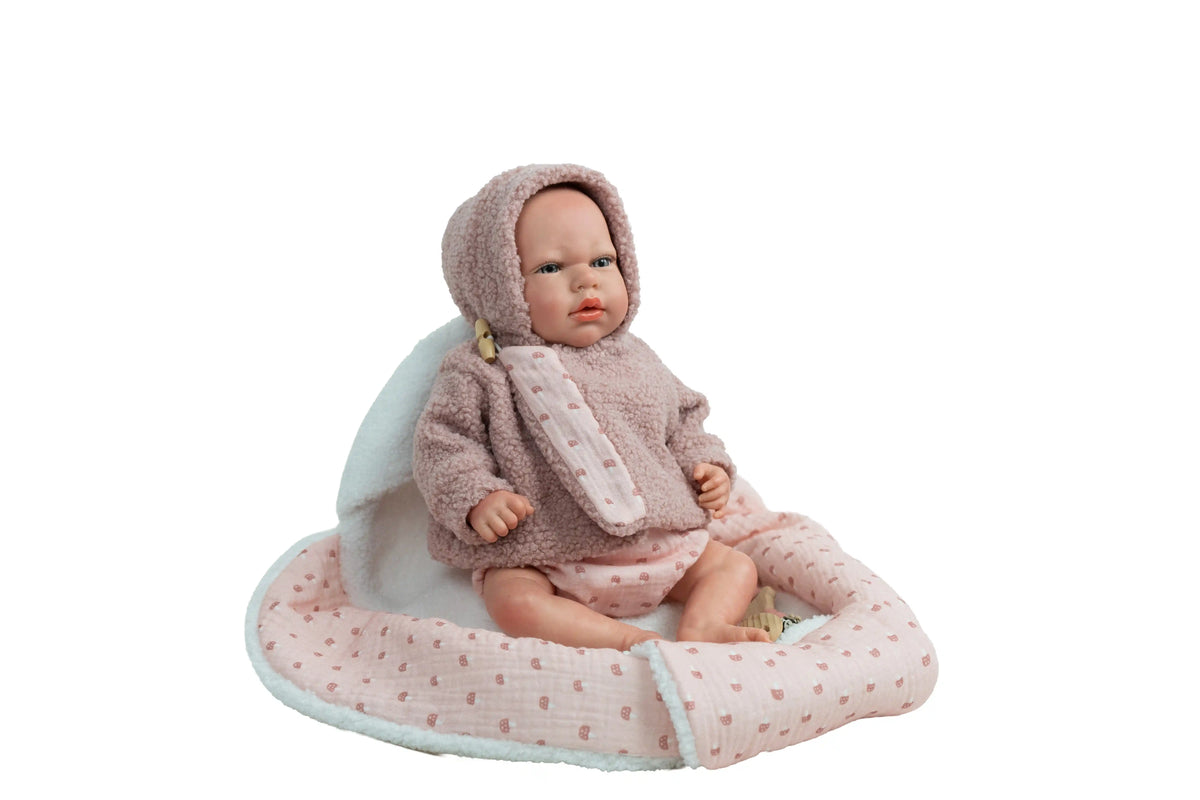 Muñeca Reborn Luna Rosa de Muñecas Arias sentada sobre la manta nido con su conjunto rosa