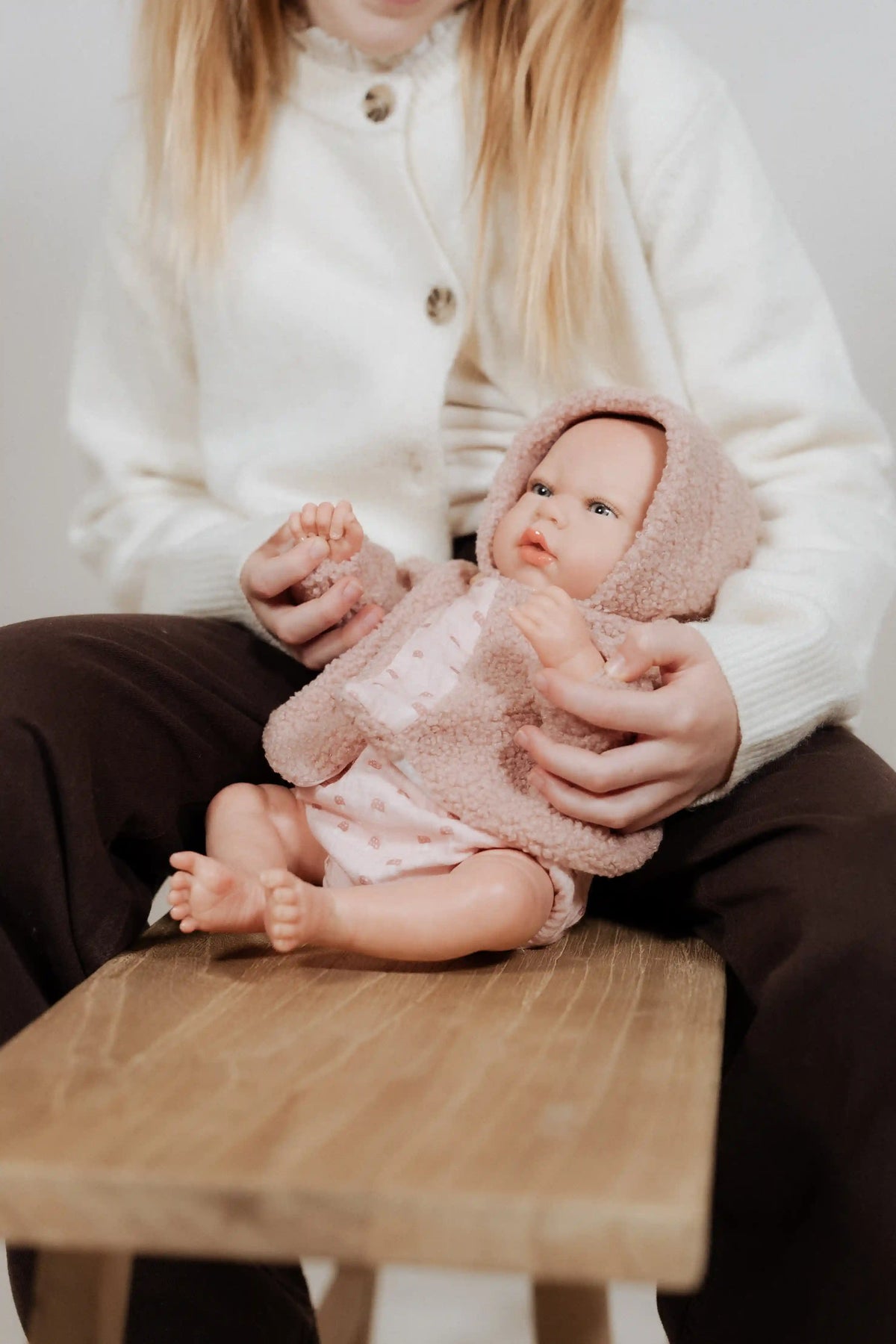 Niña sujetando la Muñeca Reborn Luna Rosa de Muñecas Arias mientras la muestra sentada