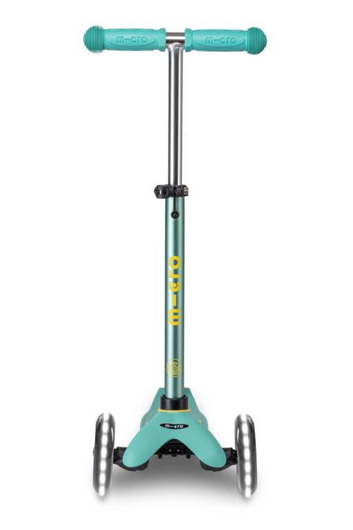 Patinete manual verde para niños con ruedas que brillan y altura regulable.