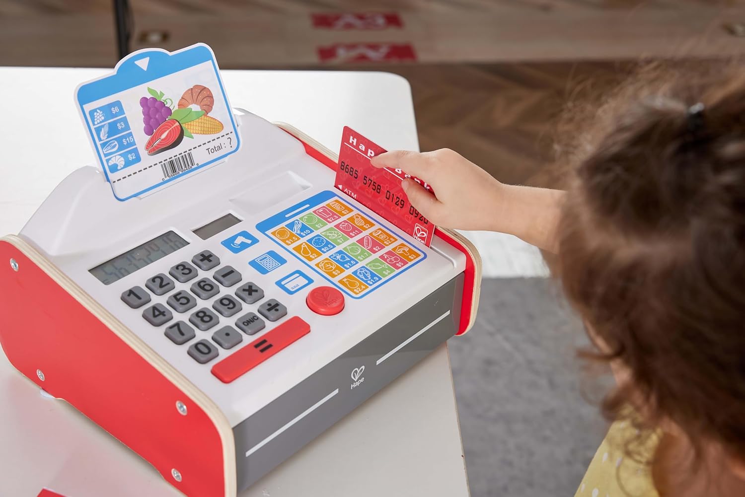 Niño jugando a las tiendas y aprendiendo matemáticas básicas con la registradora de madera Hape.