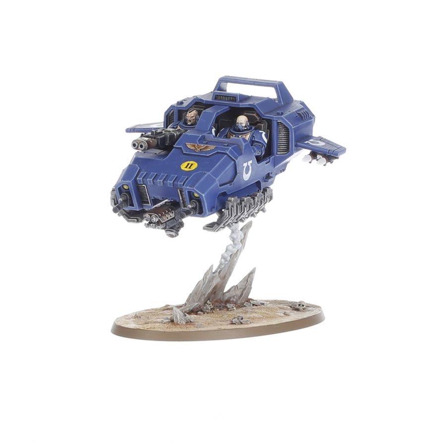 Vista frontal del Land Speeder azul de Warhammer 40,000, con sus pilotos y armamento sobre una base ovalada.