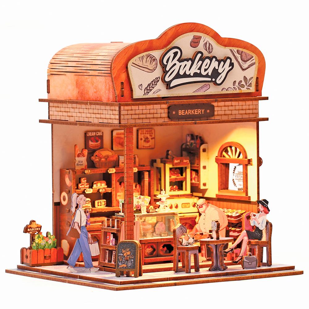 Maqueta de madera 3D Bakehouse de Graine Creative iluminada, con escaparate de panes, mesa y personajes en miniatura.