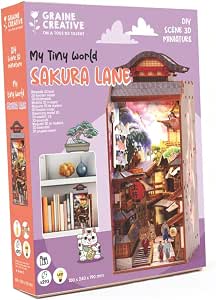 Caja de la maqueta Sakura Lane de Graine Créative, con el book nook iluminado y ejemplo de colocación entre libros.