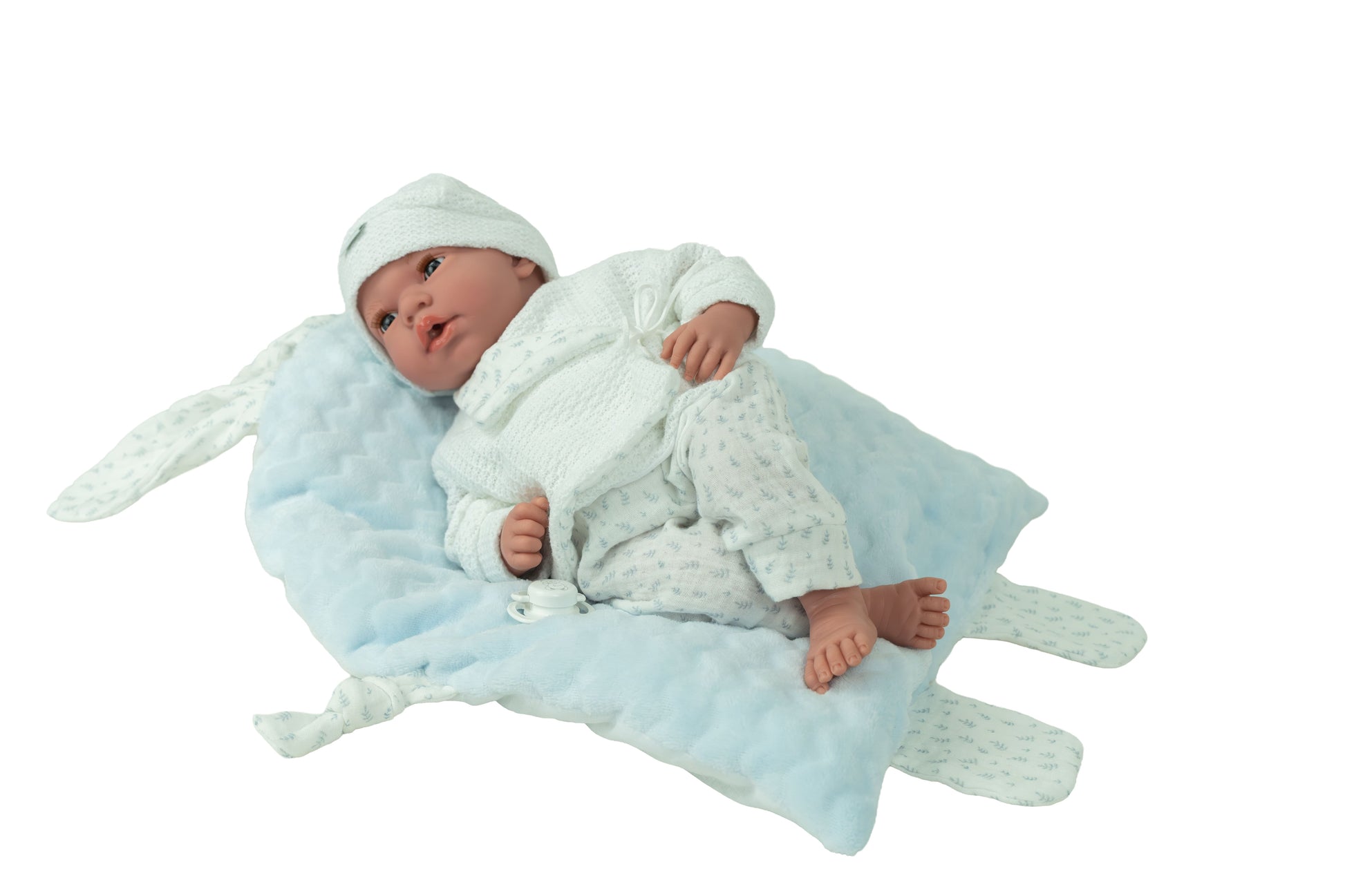 Muñeca Andie Elegance Arias recostada sobre cojín azul de orejitas, detalle de ropita blanca con estampado y pies de vinilo