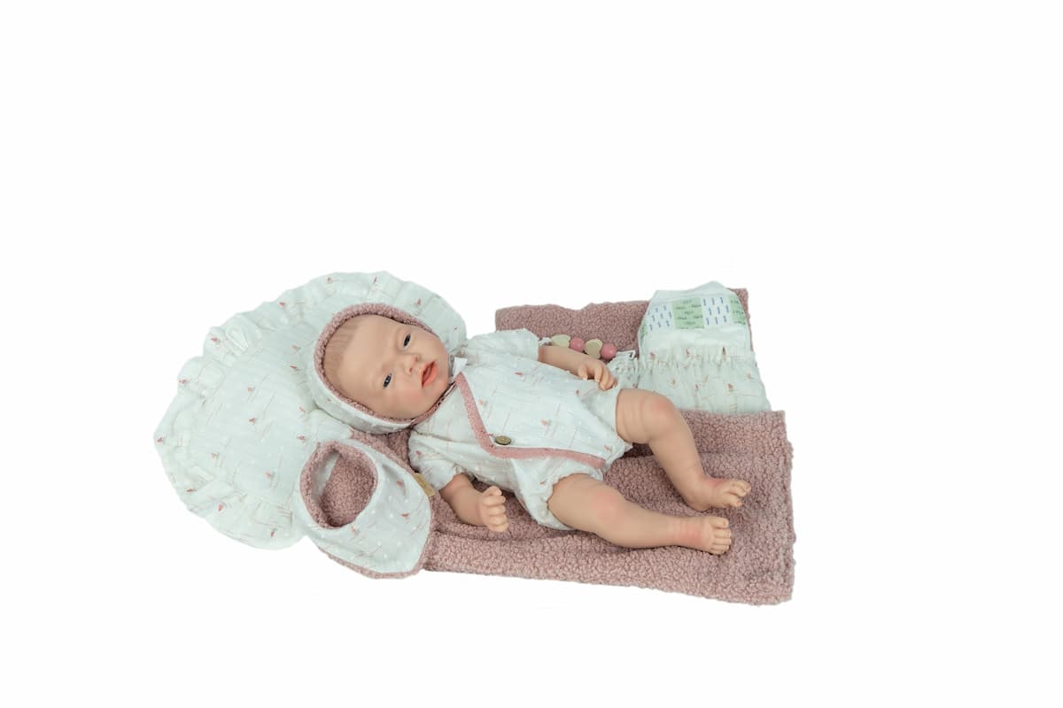 Reborn Aitana de Arias 98204 tumbada sobre una superficie clara, vista lateral de cuerpo completo.