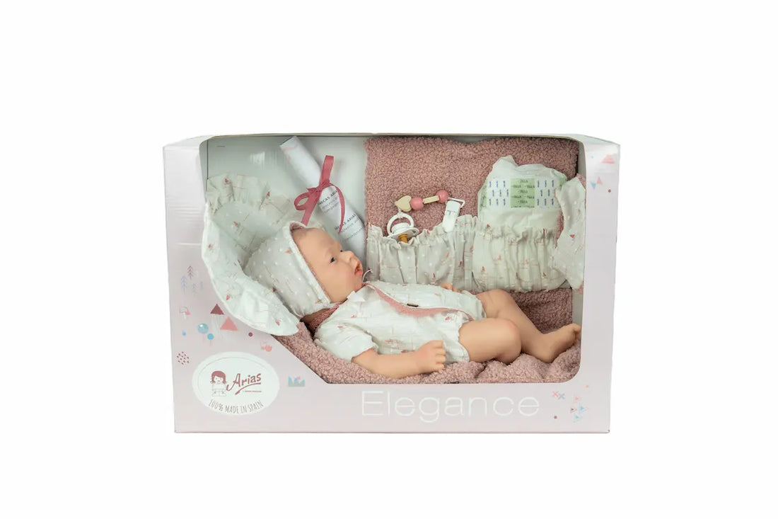 Reborn Aitana de Arias 98204 tumbada boca arriba con gorrito blanco sobre una manta clara.