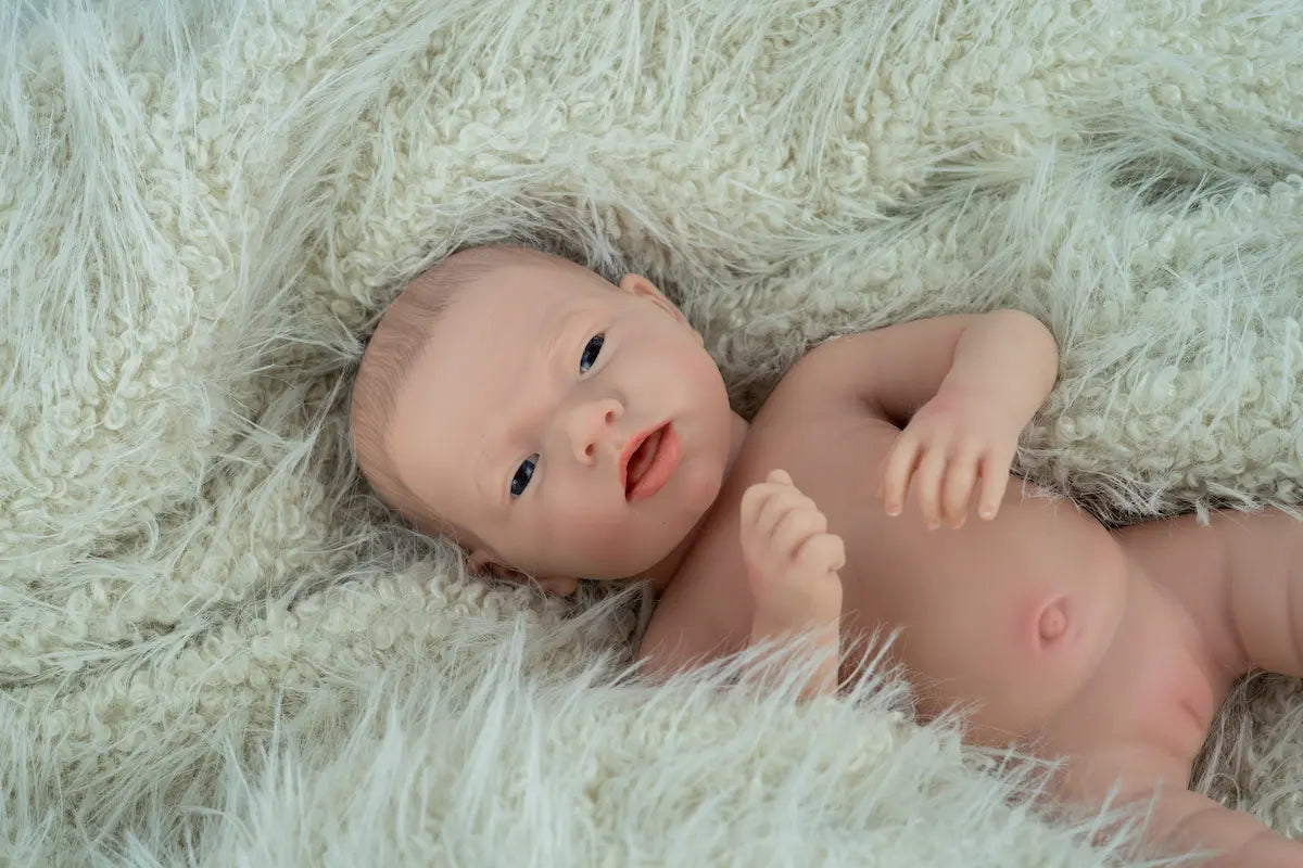 Reborn Aitana de Arias 98204 tumbada sobre una manta verde clara, vista de cerca.
