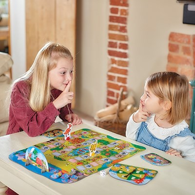 Dos niños y un adulto riendo mientras juegan a Dino-Snore-Us de Orchard Toys, practicando el respeto de turnos en grupo