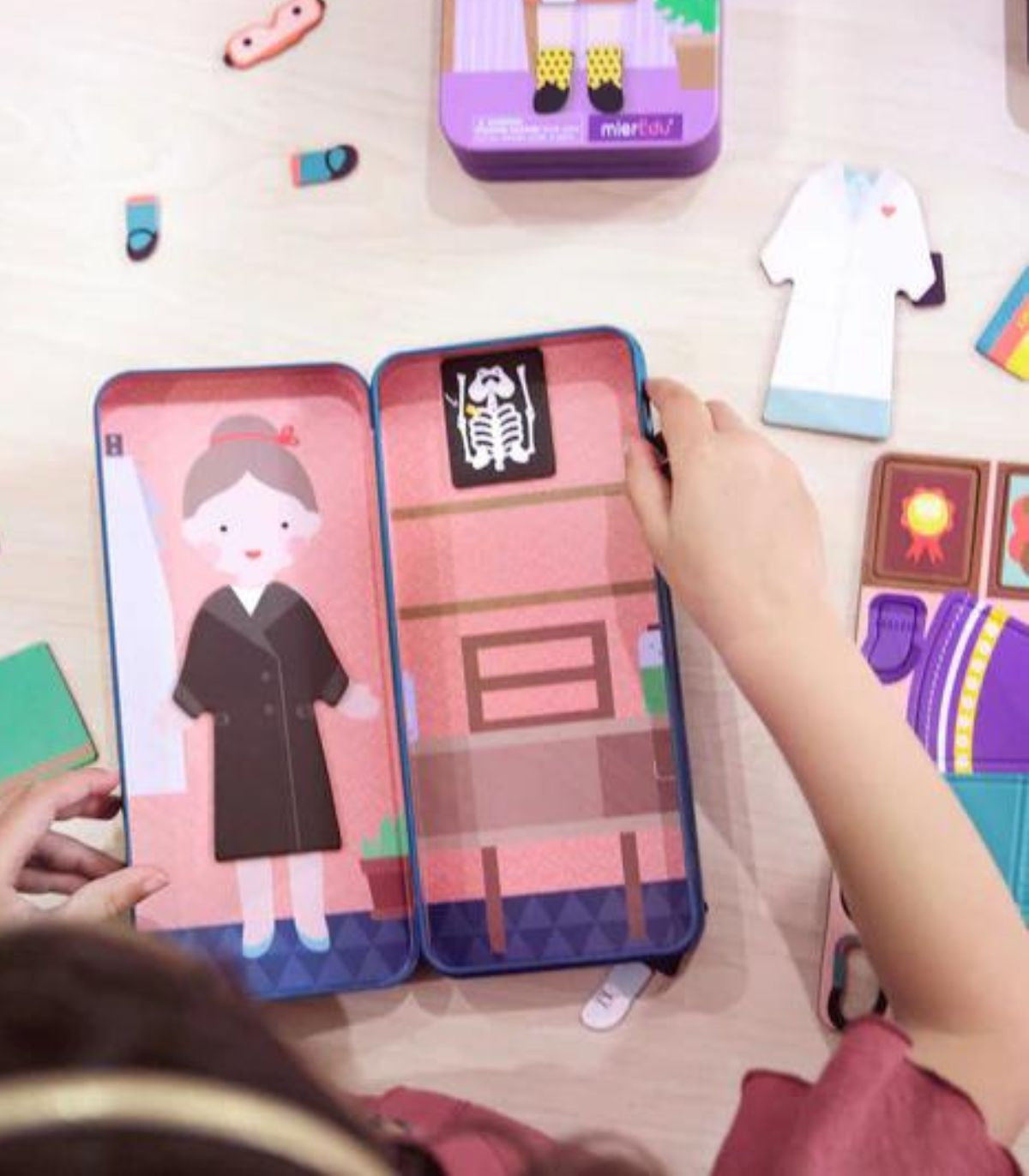 Puzle magnético Científico Curioso de mierEdu en uso, con manos infantiles manipulando la caja abierta y piezas alrededor.