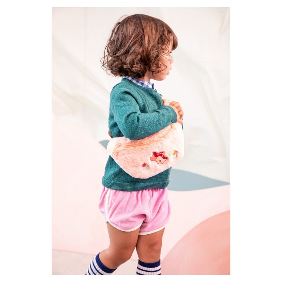 Niño con jersey verde llevando la riñonera rosa Stella la Cierva de Lilliputiens cruzada sobre el cuerpo.
